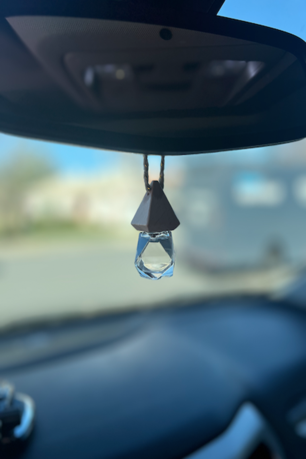 Car hanging air freshener shaped like a crystal droplet on a car's rearview mirror.