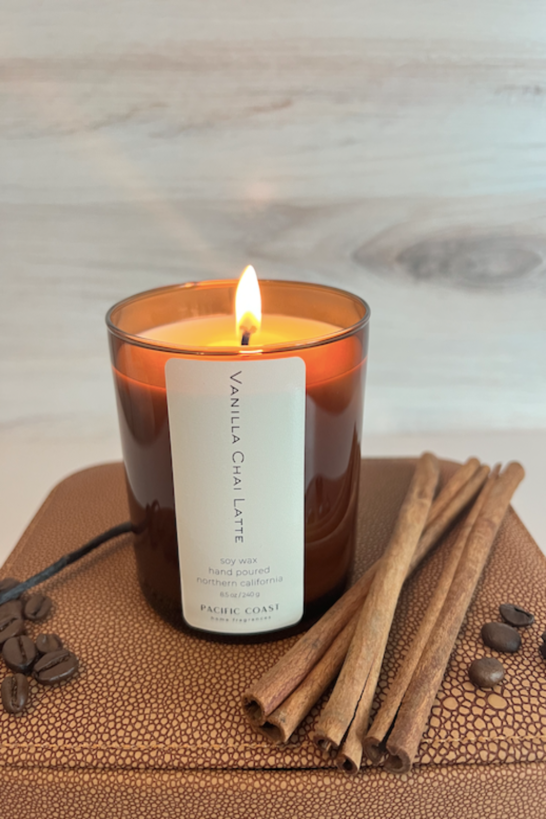 A lit vanilla chai latte scented candle with a label that reads 'VANILLA CHAI LATTE' and '8.5 oz.